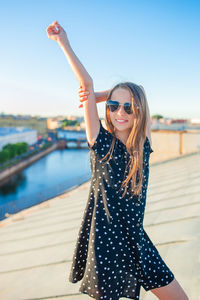 Young woman wearing sunglasses while standing against sky