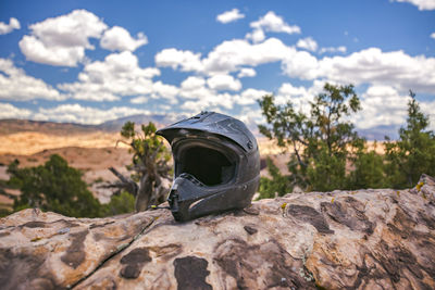 Close up of crash helmet on rock against sky