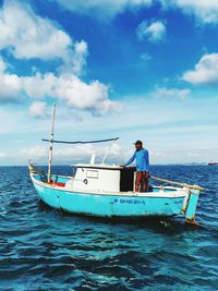 Man on fishing boat in sea against sky