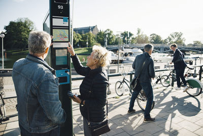 Senior couple operating bike vending machine on sidewalk in city