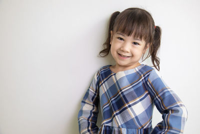 Portrait of smiling girl standing against white background