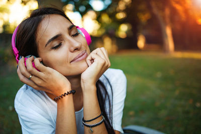 Young woman with headphone on grass outdoors