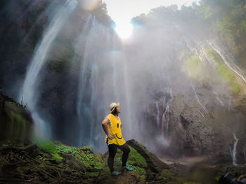 Woman standing by waterfall in forest