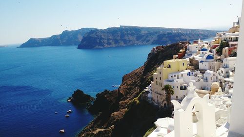 Buildings on mountain by sea at santorini against sky