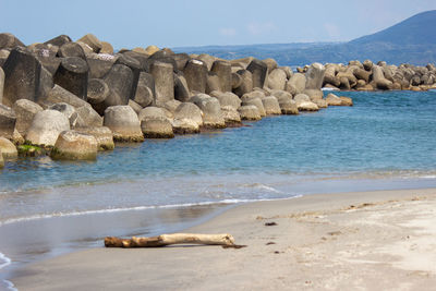Rocks on shore by sea against sky