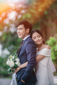 Portrait of couple with pink flowers against blurred background