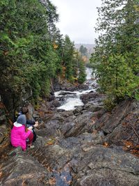 Rear view of woman amidst rocks against trees