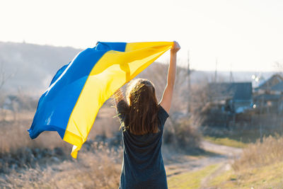 Woman holding a yellow and blue flag of ukraine in outdoors