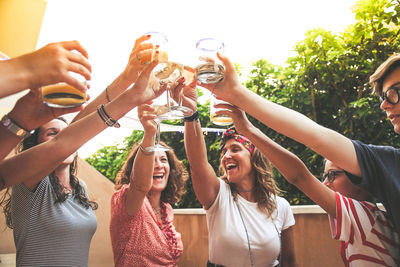 Cheerful friends toasting drinks while standing outdoors