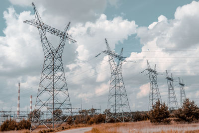 Low angle view of electricity pylon on field against sky