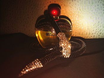 Close-up of illuminated lighting equipment on table against wall