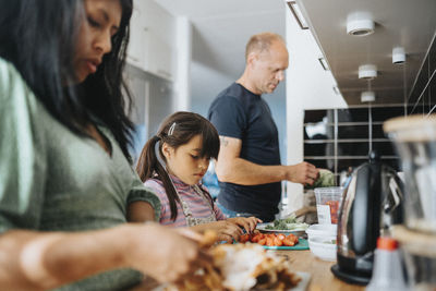 Family with daughter preparing meal together at home