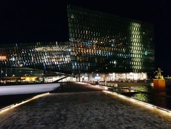 Illuminated road amidst buildings in city at night