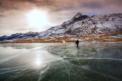 Person walking on snowcapped mountain against sky