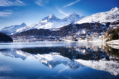 View of the city of saint moritz with snowcapped mountains reflected in the lake.