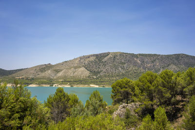 Scenic view of lake and mountains against blue sky