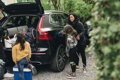 Full length of woman with children in car