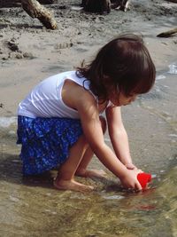 Girl filling water in glass at beach