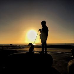 Silhouette men on beach against sky during sunset