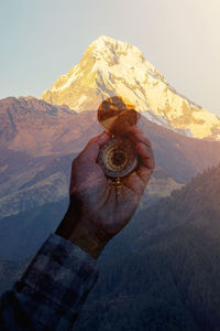 Double exposure image of hand holding navigational compass with mountain 