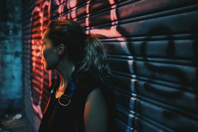 Woman standing by shutter at night