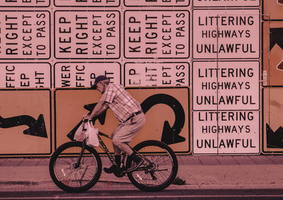 Side view of man with bicycle sign on wall