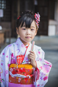 Close-up portrait of girl wearing kimono outdoors