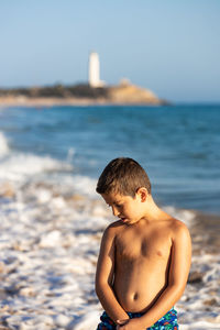 Portrait of a little kid on the ocean with a lighthouse background