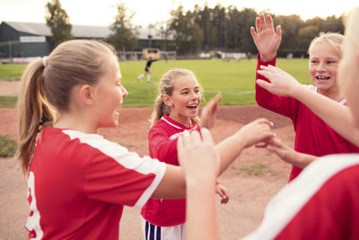 Playful female soccer players standing against field