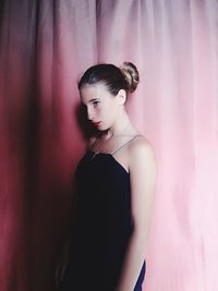 Girl looking away while standing by curtain at home