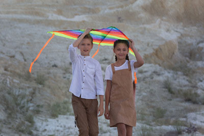 Children go sheltered from the rain with kite.