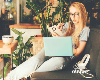 Smart blonde girl with long hair on a sofa with a laptop in a cafe.