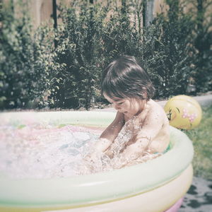 Boy in swimming pool by plant