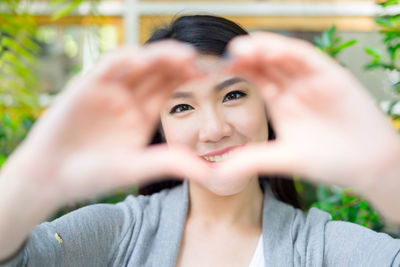 Portrait of smiling young woman making heart shape