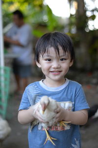 Portrait of smiling boy holding chicken