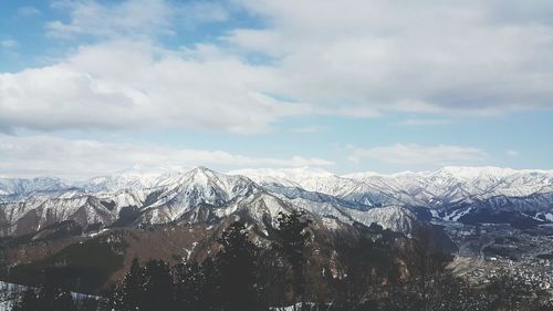 Scenic view of snowcapped mountains against cloudy sky