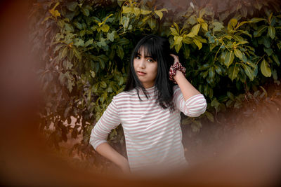 Portrait of smiling young woman standing against plants