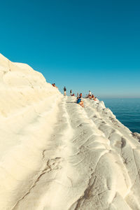 People on beach against clear blue sky