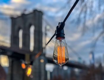 Close-up of illuminated lighting equipment hanging against sky