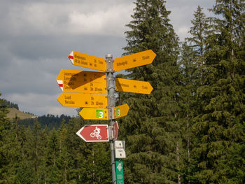 Road sign against trees and sky