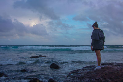 Rear view of man standing on beach against sky