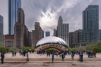 People on modern buildings in city against sky