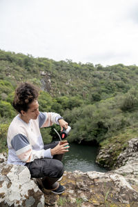 Woman drinking mate while relaxing sitting outdoors in nature.