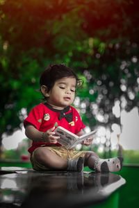 Cute girl looking down while sitting against blurred background