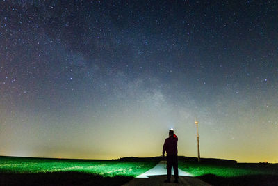 Man standing on field against sky at night