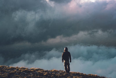 Rear view of man standing on mountain against sky