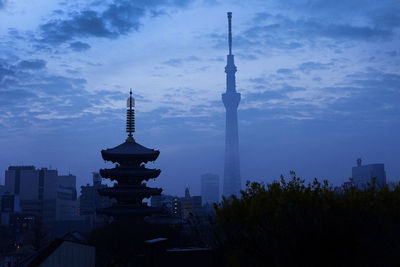 Communications tower and temple against blue sky at dusk