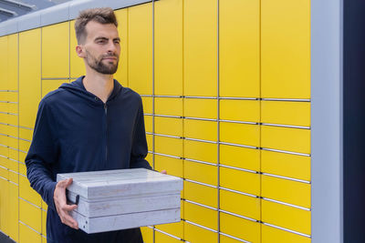 Portrait of young man standing against yellow wall