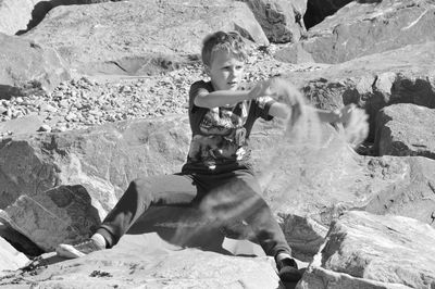 Boy sitting on rock 