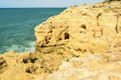 Rock formation on beach against sky